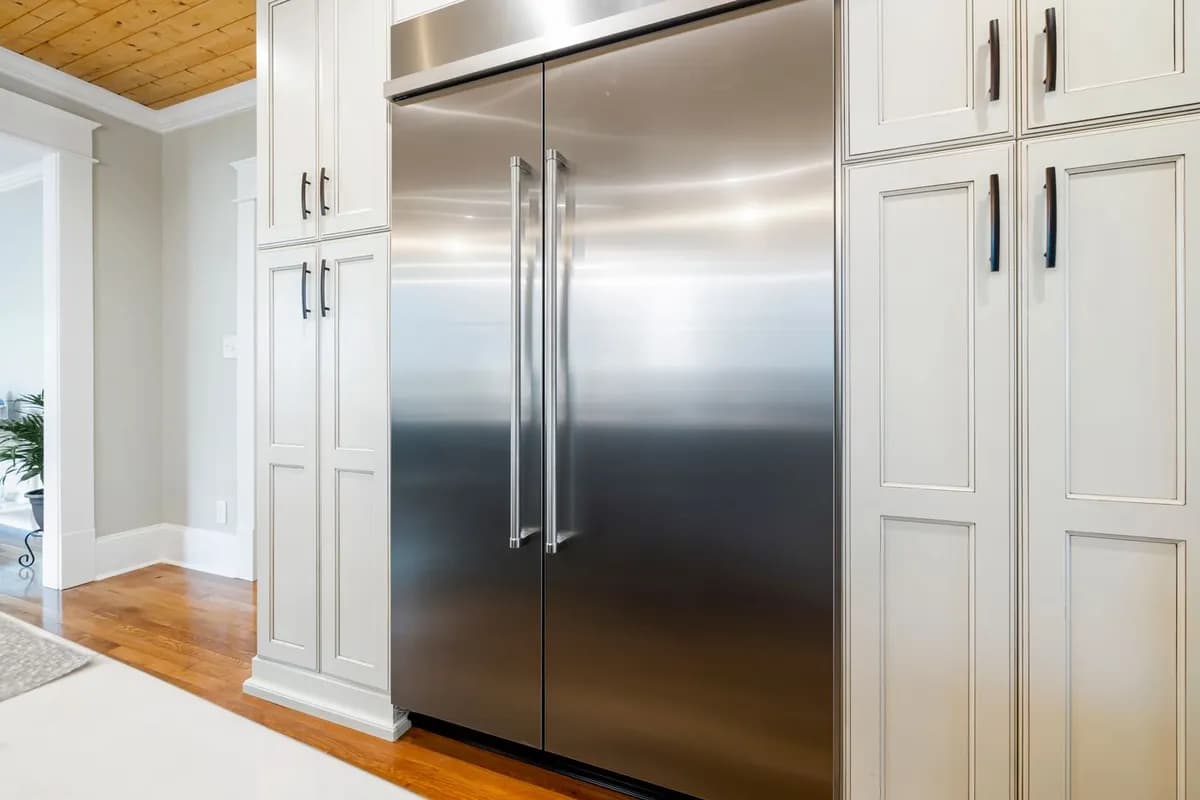 Built-in stainless steel refrigerator column between white cabinets